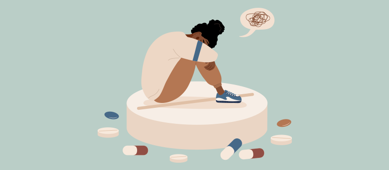 A woman looking sad while sitting on a Wellbutrin pill